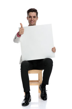 seated businessman holding blank board makes the ok sign
