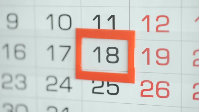 Woman's hand in office changes date at wall calendar. Changes 107 to 18
