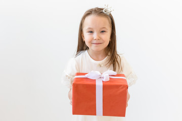 people, children and holiday concept - portrait of happy little girl holding a gift box over white background