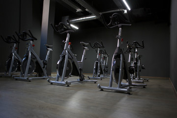 Fototapeta na wymiar Modern gym interior with equipment. Row of training exercise bikes detail, backlight. Healthy lifestyle concept