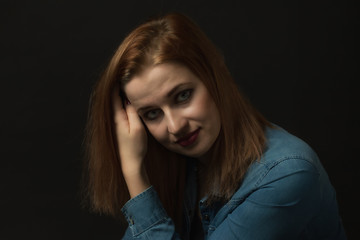 Low key portrait of posing young attractive woman holding her hair and looking at the camera on the black background. Horizontally. 