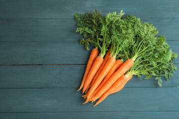 Ripe carrots on wooden background, space for text