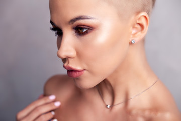 Closeup sexy blonde model with bright make-up, bare shoulders and short hair with shaved temples in...