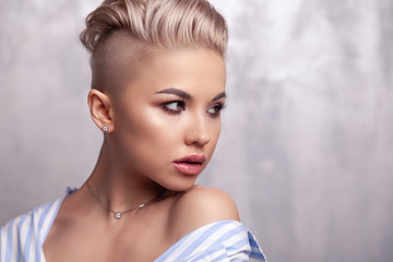 Closeup sexy blonde model with bright make-up, bare shoulders and short hair with shaved temples in...