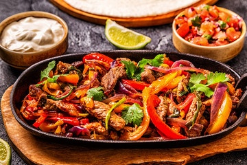 FAJITAS with colored pepper and onions, served with tortillas.