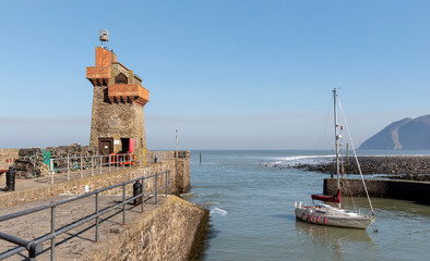 Fototapeta na wymiar Lynmouth, North Devon, England, UK. March 2019. Lynmouth pier on the West Lyn River with the historic Rhenish Tower