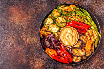 Grilled vegetables on a plate with sauce.