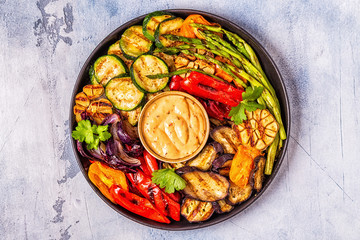 Grilled vegetables on a plate with sauce.