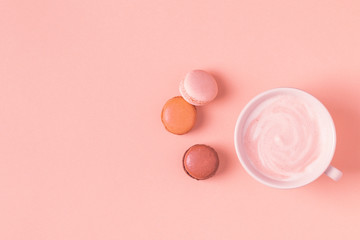 Cup of coffee with macaroons on pastel background.
