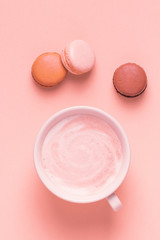Cup of coffee with macaroons on pastel background.