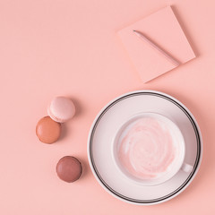 Cup of coffee with macaroons on pastel background.