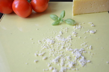 Italian food background with tomatoes, basil, parmesan. Ingredients onellow table Copy space Top view