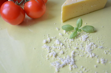 Italian food background with tomatoes, basil, parmesan. Ingredients onellow table Copy space Top view