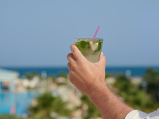 Man's hand with mojito against wonderful seaview.