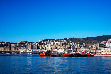 Fototapeta na wymiar Beautiful view of the rocky mountains, the Italian city of Genoa, the port and the red boats. Blue sky with white cloud. Blue Ocean.