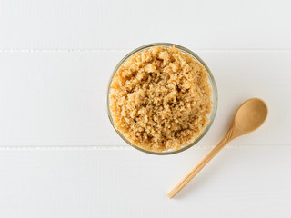 Cooked quinoa cereal in a glass bowl on a white table with parsley leaves. The view from the top. Flat lay.