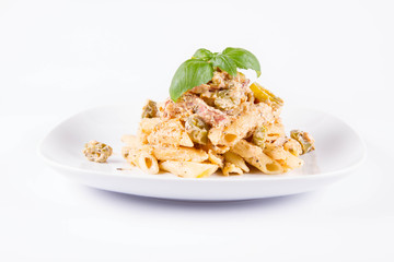 Pasta - penne with white cream sauce with bacon and jalapeño peppers on a plate, decorated with fresh basil	