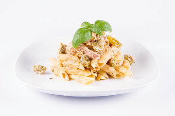 Pasta - penne with white cream sauce with bacon and jalapeño peppers on a plate, decorated with fresh basil	