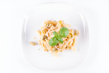 Pasta - penne with white cream sauce with bacon and jalapeño peppers on a plate, decorated with fresh basil	