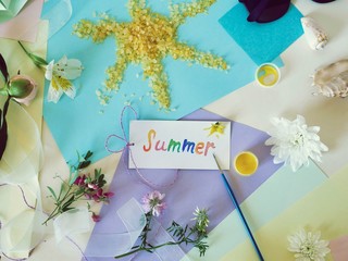 Postcard summer, the sun from sea salt, fresh flowers, colored paper, brushes - the concept of congratulations on the summer, seasonal decorative composition