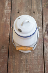 old enameled milk container stands on a wooden table