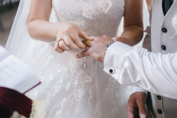 Obraz na płótnie Canvas Bride puts wedding ring on groom's finger