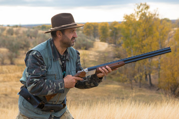 Hunter with a hat and a gun in search of prey in the steppe	