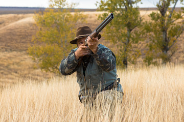 Hunter with a hat and a gun in search of prey in the steppe	