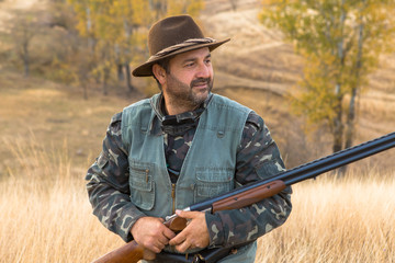 Fototapeta premium Hunter with a hat and a gun in search of prey in the steppe 