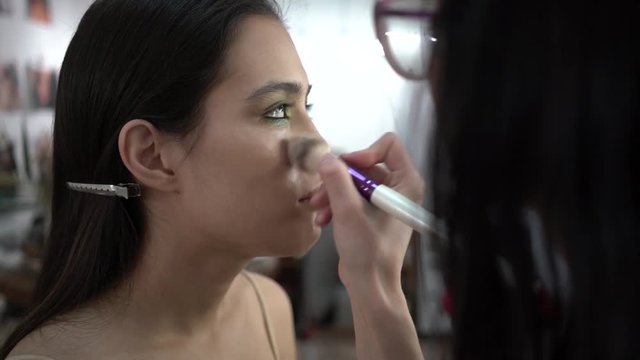 makeup artist makes makeup model
