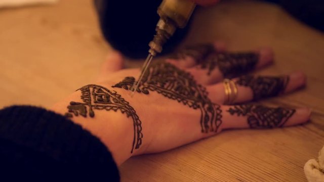 Woman getting henna tattoo. Close shot of hands and henna being applied. Morocco.