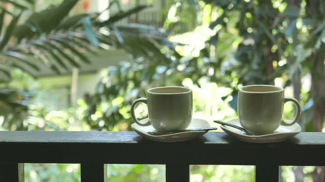 Couple of coffee mugs with saucer on the Balcony with a beautiful green plantation background