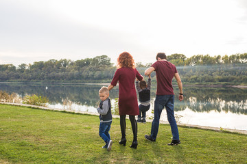 Parent, childhood and nature concept - Family playing with two sons by the water
