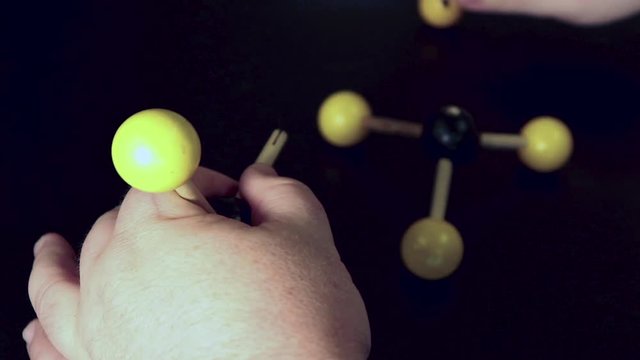 Ball and stick model of methane being modified to form ethane and then moved around on a black lab bench
