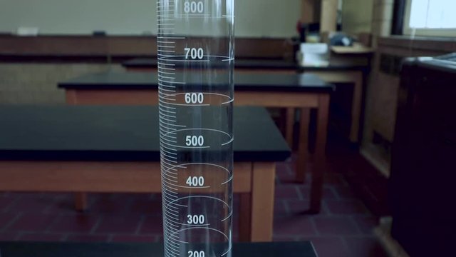 Lifting up along a 1000mL graduated cylinder on a black lab bench in a high school chemitry lab