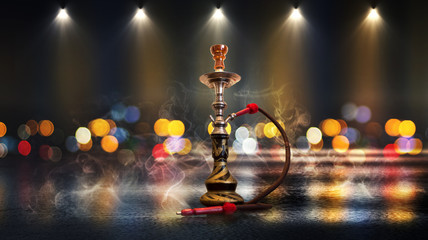 Hookah with smoke on the background of an empty scene, wet asphalt and colored neon light, blurry lights of the night city, bokeh