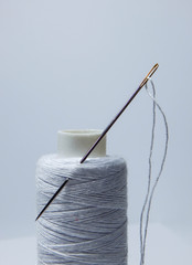 spool of thread and needle on white background