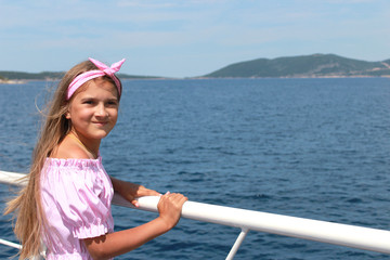 happy little girl sailing in a boat smiling at the sea on summer cruise