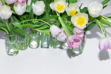 Top view of the bouquets of tulips in glass jars on a white background.