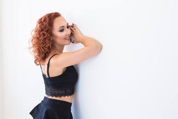 People and fashion concept - Redhead woman in black shirt and skirt posing isolated on white background