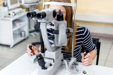 a young woman examines the eyes of an ophthalmologist on a slit lamp