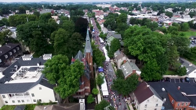 Aerial up main street past red brick Mary Dixon Chapel spire, large crowds at the Lititz Craft Show Lititz Lancaster County Pennsylvania Concept Americana, small town, crowds, lifestyle, commerce