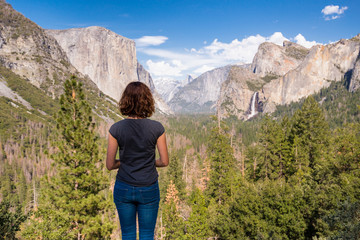 Naklejka premium Young woman is looking at Yosemite valley from Tunnel View in Yosemite National park, United states of America