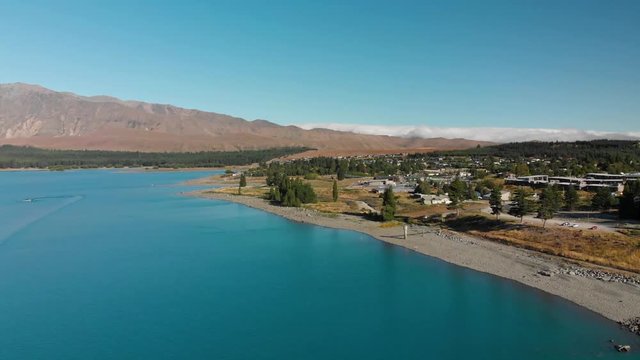 SLOWMO - Aerial shot of Lake Tekapo, New Zealand and its Beautiful Turquoise Blue Water wiht mountains in background