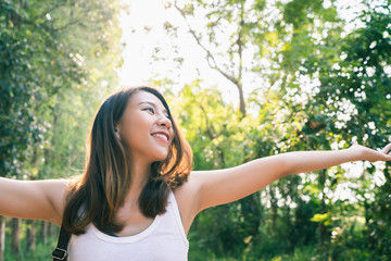 Happy young Asian woman traveler with backpack walking in forest. Hiker Asian woman with backpack walking on path in summer forest. Adventure backpacker travel people concept.