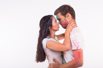 Holiday, holi and people concept - Happy couple having fun covered in paint on white background