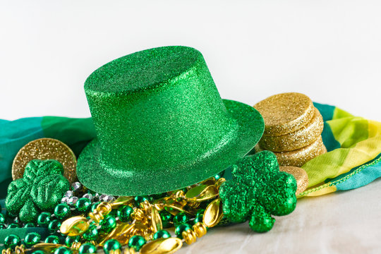 Close up view of green top hat on top of gold, silver, and green beads with shamrocks and gold coins. - Powered by Adobe