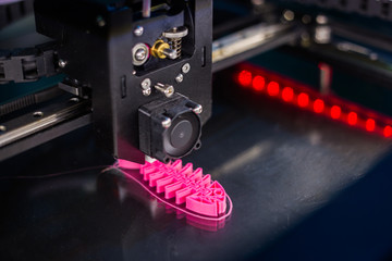 Automatic three dimensional 3D printer machine printing plastic model of pink fish skeleton at...