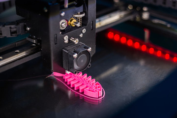 Automatic three dimensional 3D printer machine printing plastic model of pink fish skeleton at modern technology exhibition. 3D printing, additive technologies and futuristic concept