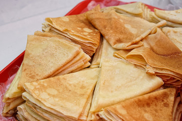 A lot of pancakes on a red tray at the Slavic festival of early spring - carnival